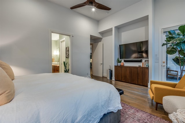 bedroom with ensuite bathroom, wood finished floors, and a ceiling fan