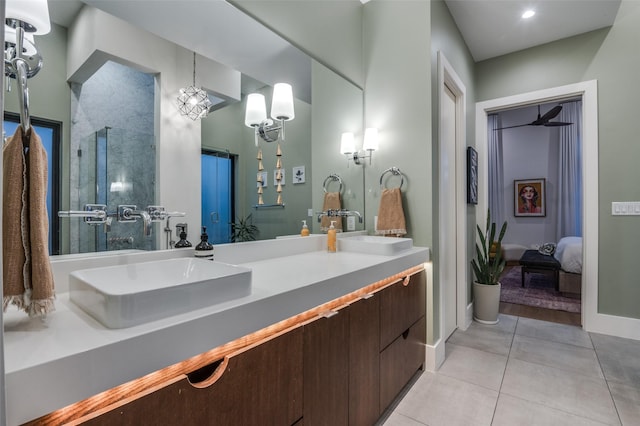 ensuite bathroom with double vanity, a sink, a shower with door, and tile patterned floors