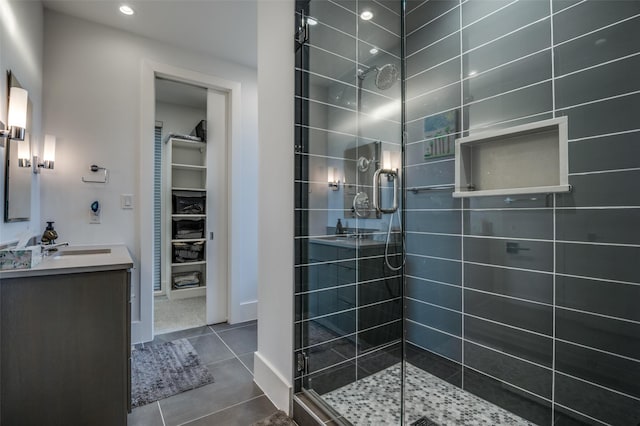 bathroom with tile patterned floors, a shower stall, a spacious closet, and vanity