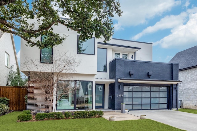 view of front of home featuring a garage, concrete driveway, fence, a front lawn, and stucco siding