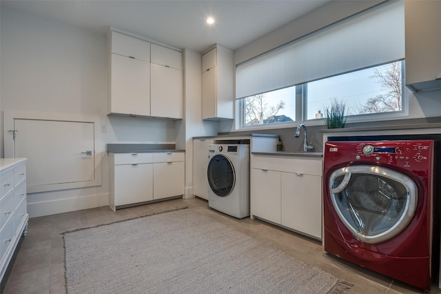 clothes washing area featuring recessed lighting, independent washer and dryer, cabinet space, and a sink