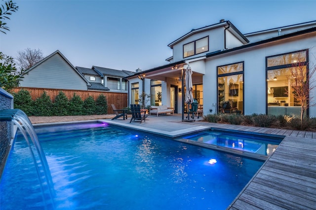 back of property with a patio area, fence, a pool with connected hot tub, and stucco siding