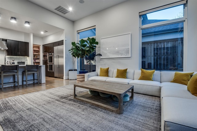 living area with light wood-style floors and visible vents