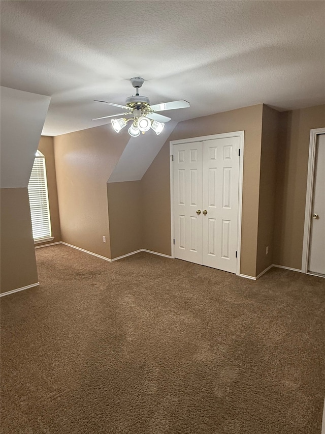 additional living space featuring baseboards, carpet, a textured ceiling, and ceiling fan