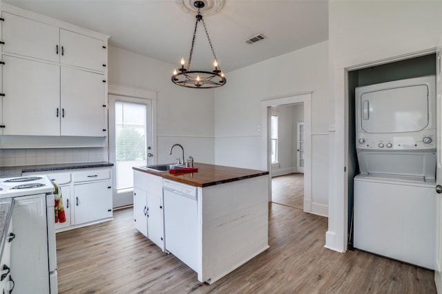 kitchen featuring stacked washer / drying machine, light wood-style flooring, a sink, wood counters, and white appliances