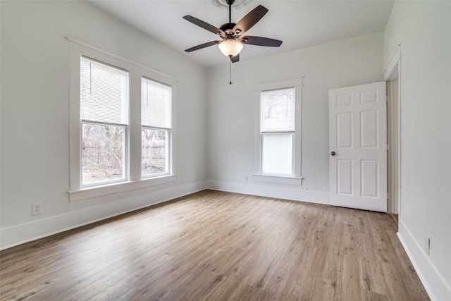 empty room with baseboards, ceiling fan, light wood-style floors, and a healthy amount of sunlight