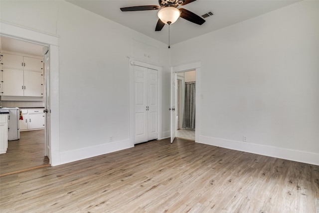 empty room featuring light wood finished floors, baseboards, visible vents, and a ceiling fan