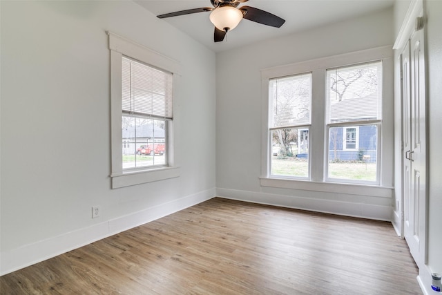 spare room featuring a ceiling fan, light wood-style flooring, and baseboards