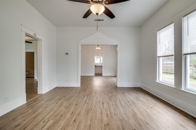 unfurnished room with baseboards, ceiling fan with notable chandelier, visible vents, and light wood-style floors