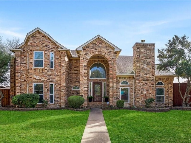 traditional home with brick siding, a chimney, and a front yard