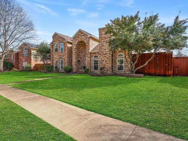 view of front of house with a front yard, brick siding, and fence