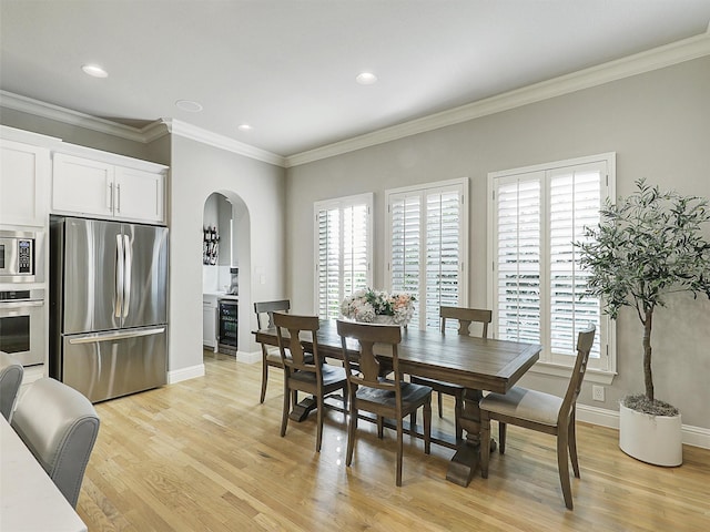 dining area with arched walkways, crown molding, light wood-style floors, beverage cooler, and baseboards