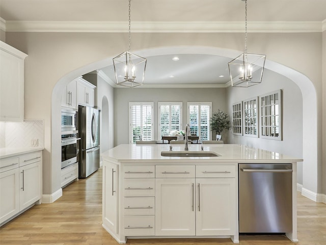 kitchen with appliances with stainless steel finishes, a sink, light wood-style flooring, and an inviting chandelier