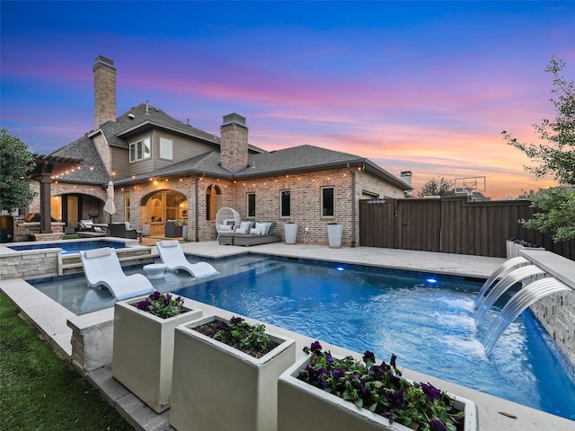 pool at dusk with an in ground hot tub, fence, an outdoor living space, a fenced in pool, and a patio area