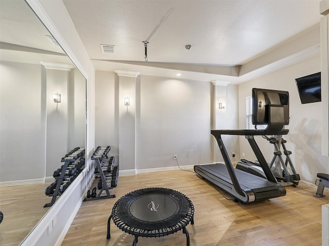 workout area with visible vents, light wood-style flooring, and baseboards