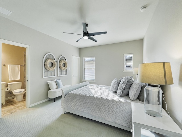 bedroom featuring baseboards, connected bathroom, a ceiling fan, and light colored carpet