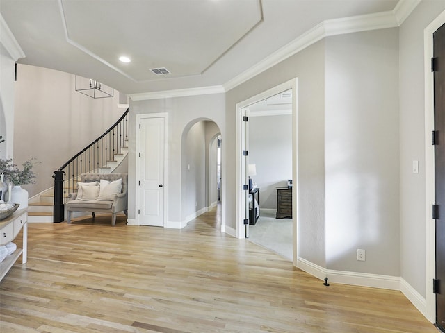 foyer with visible vents, arched walkways, baseboards, light wood-style flooring, and stairs