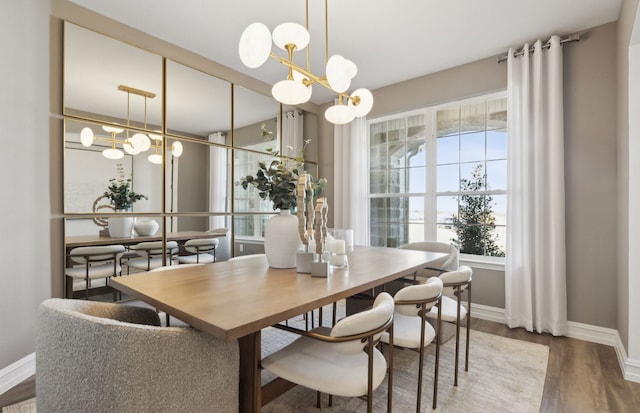 dining area featuring baseboards, wood finished floors, and an inviting chandelier