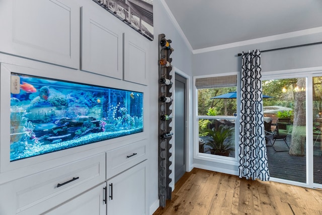 interior space with light wood-style floors, white cabinets, and crown molding