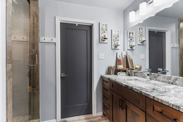 bathroom featuring a stall shower, vanity, and wood finished floors