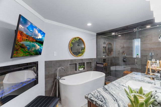 full bathroom with vanity, tile walls, a freestanding bath, ornamental molding, and a stall shower