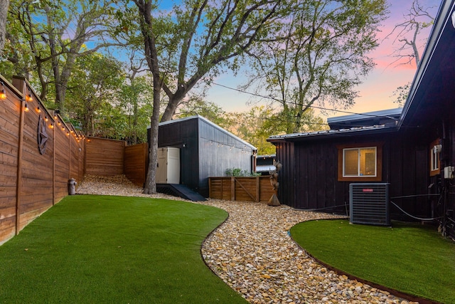 view of yard featuring a storage shed, an outdoor structure, a fenced backyard, and central air condition unit