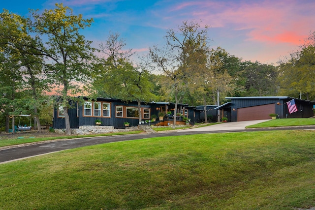 mid-century inspired home with driveway, a lawn, and an outdoor structure