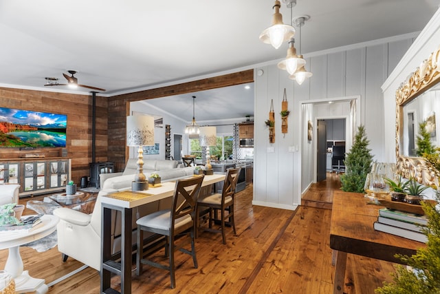 dining room featuring a wood stove, wood walls, a ceiling fan, and hardwood / wood-style floors