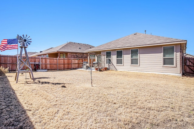 back of house featuring a shingled roof, a fenced backyard, and a patio