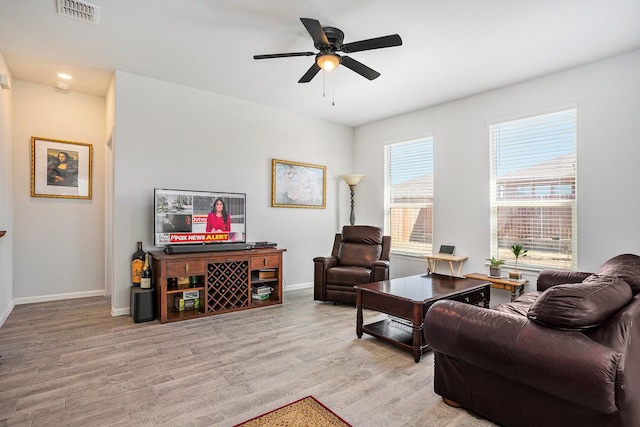 living area with baseboards, visible vents, ceiling fan, and light wood finished floors