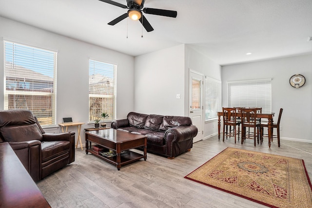 living room with a ceiling fan, baseboards, and wood finished floors