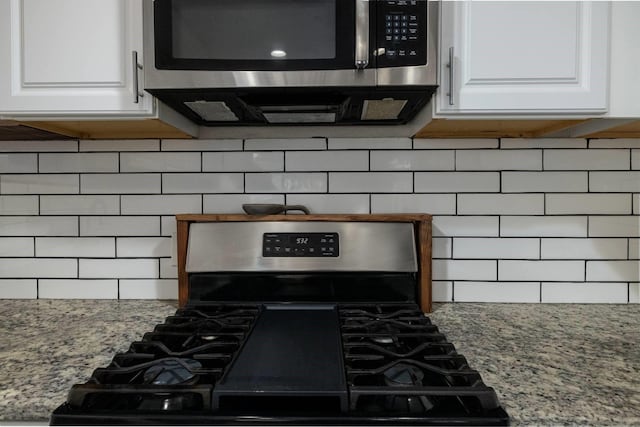 kitchen with appliances with stainless steel finishes, white cabinets, decorative backsplash, and light stone countertops