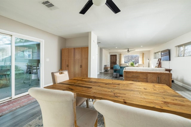 dining space with a ceiling fan, wood finished floors, visible vents, and baseboards