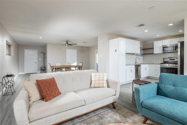 living area with recessed lighting, visible vents, light wood-style flooring, and baseboards