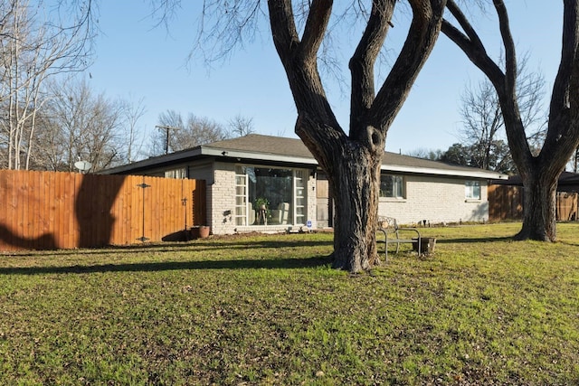 exterior space with a yard, fence, and brick siding