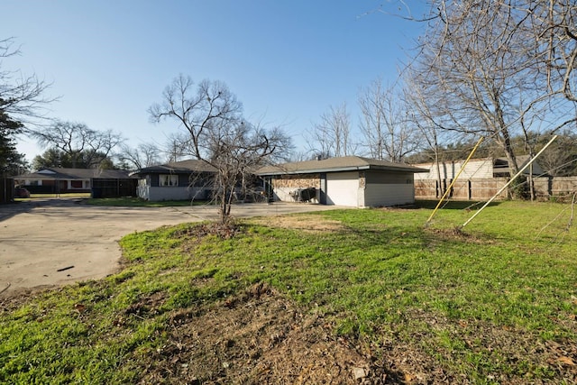 view of front facade with a carport, driveway, a front lawn, and fence