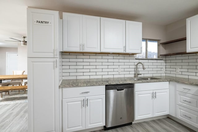 kitchen with white cabinets, a sink, stainless steel dishwasher, and open shelves