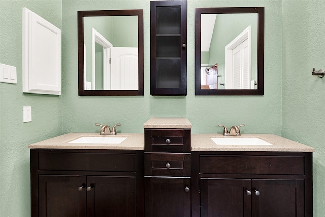 bathroom with two vanities, a sink, and a textured wall