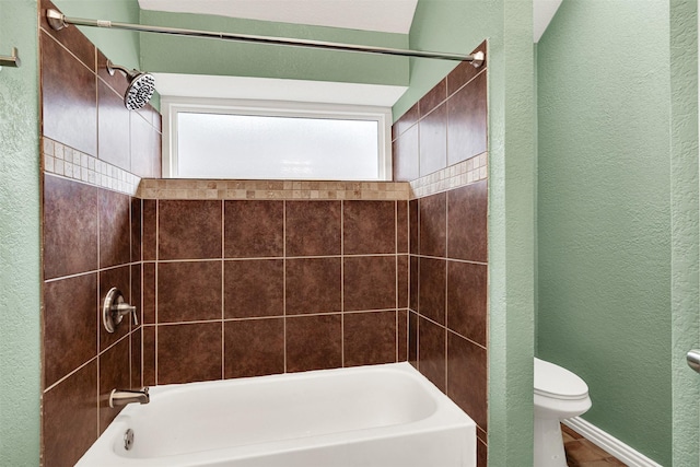 bathroom featuring a textured wall, shower / tub combination, and toilet