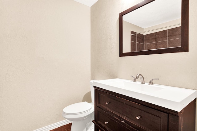 bathroom with baseboards, a textured wall, vanity, and toilet