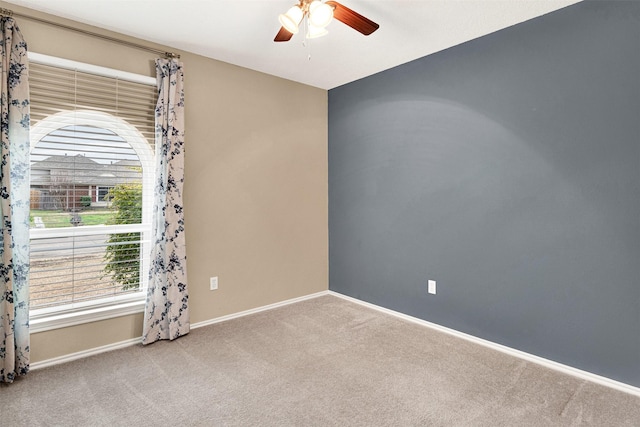 carpeted empty room featuring a ceiling fan and baseboards