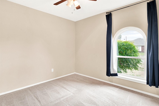 carpeted empty room with a ceiling fan and baseboards