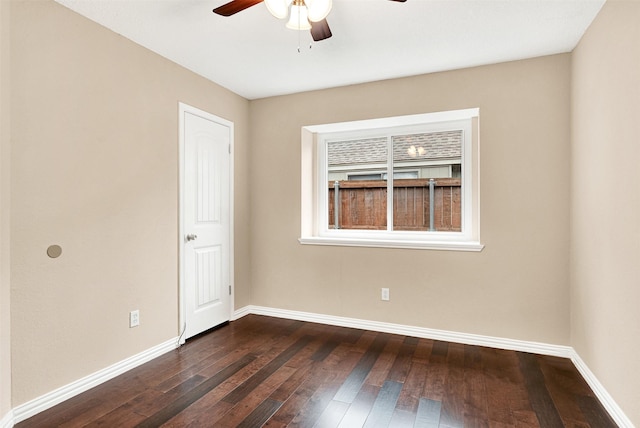 unfurnished room with dark wood-type flooring, a ceiling fan, and baseboards