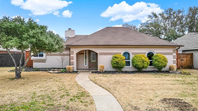 single story home with brick siding, fence, a chimney, and a front lawn