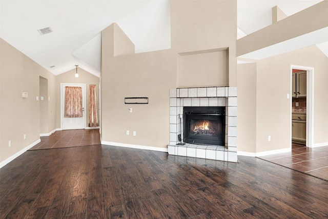 unfurnished living room with high vaulted ceiling, a fireplace, wood finished floors, visible vents, and baseboards