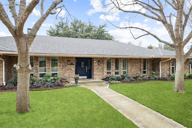 ranch-style house with a shingled roof, a chimney, a front lawn, and brick siding