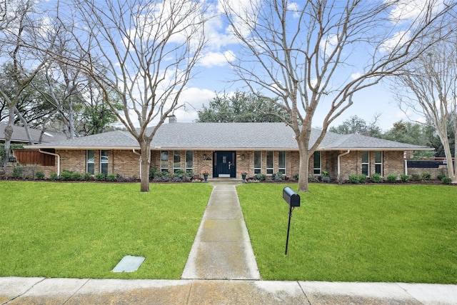 ranch-style home with brick siding, a chimney, and a front yard