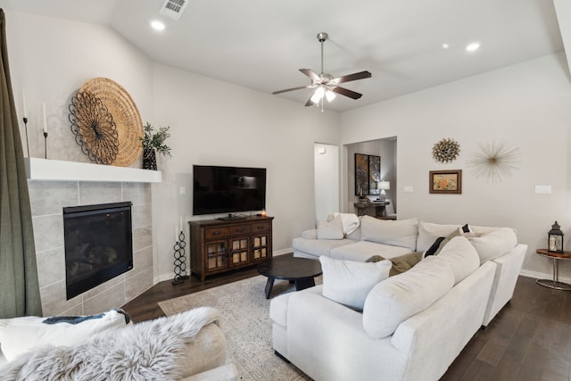 living room with baseboards, visible vents, a ceiling fan, a tile fireplace, and dark wood-style floors