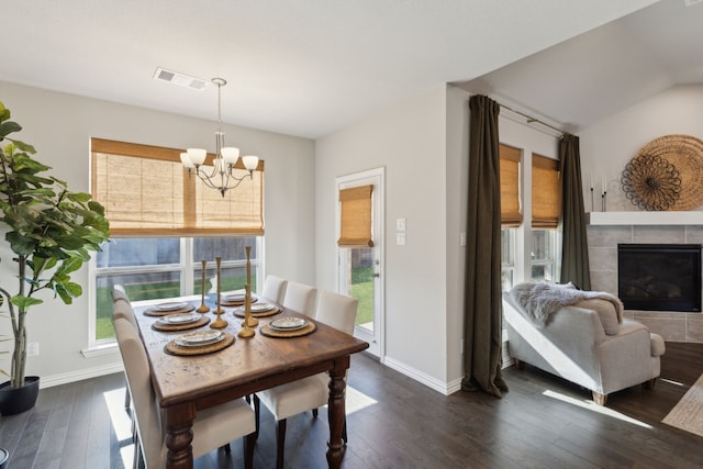 dining space with an inviting chandelier, visible vents, dark wood finished floors, and a tile fireplace