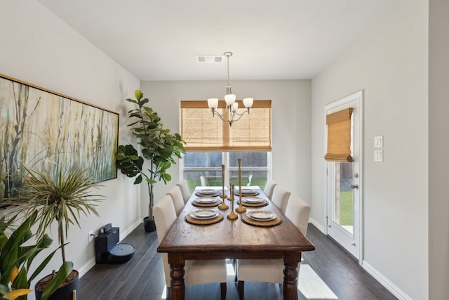 dining space featuring dark wood-style flooring, visible vents, a notable chandelier, and baseboards